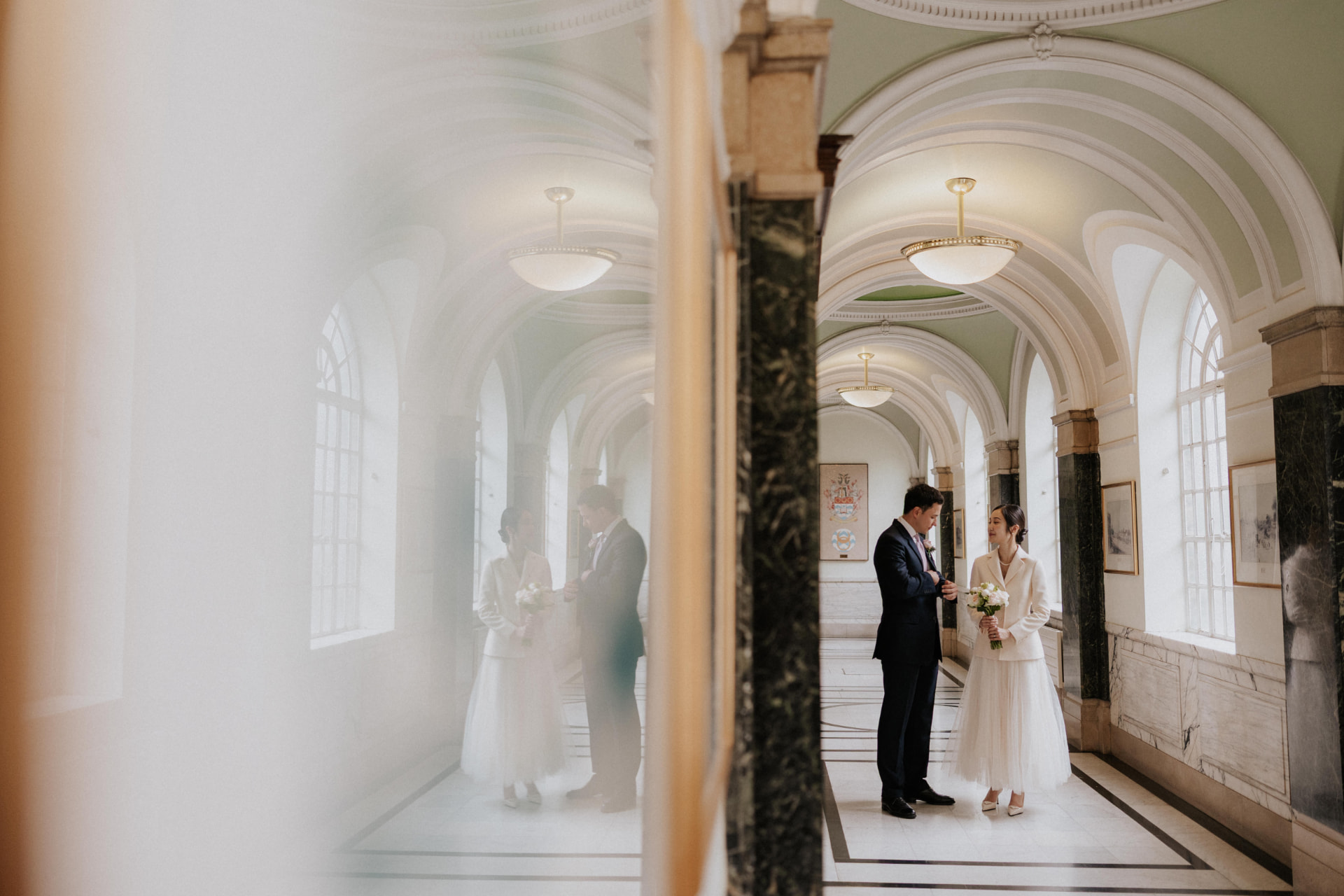 Jinny and Daniel in a bright marble corridor